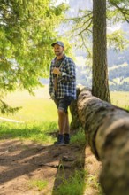 Man leaning against a tree trunk and enjoying the forest atmosphere, Alpe di Siusi, Dolomites,