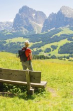 Person looking from a bench at the impressive mountain landscape, Alpe di Siusi, Dolomites, South
