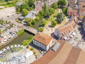 Aerial view of a summer festival with Ferris wheel, river, bridge and park, surrounded by municipal