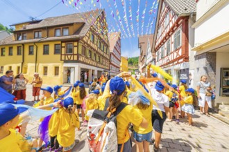 Children in yellow T-shirts and blue caps at a street parade in summer. Festive atmosphere with