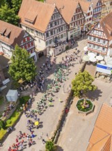 Aerial view of a village street with people in parade formation and traditional architecture, 950