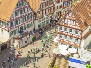 Aerial view of a group of people at a town festival, decorated with colourful balloons, 950 years