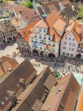 Crowd of people in front of historical buildings at a town festival, decorated with colourful