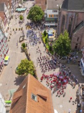 Aerial view of a celebration in a historic town with half-timbered architecture and many people,