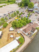Aerial view of people at an event on a green area, surrounded by trees and river, 950 years Calw,