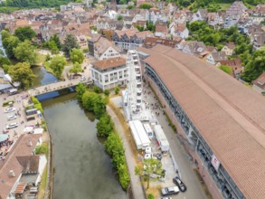 Aerial view of a town by the river with a Ferris wheel and red tiled roofs under a clear sky, 950