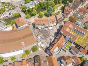 Aerial view of a town with a lively market square, numerous buildings and green trees, 950 years of