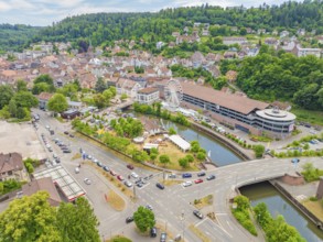 Wide view of a town with river and Ferris wheel in the middle of a green and mountainous