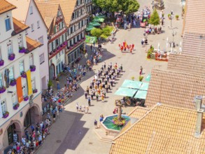 People on a square with a fountain, surrounded by decorated buildings, 950 years Calw, parade Calw,