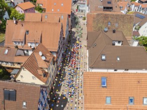 People walking on a street decorated with colourful umbrellas, 950 years Calw, parade Calw, Black