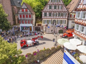 Fire engines drive through a half-timbered neighbourhood, watched by numerous spectators, 950 years
