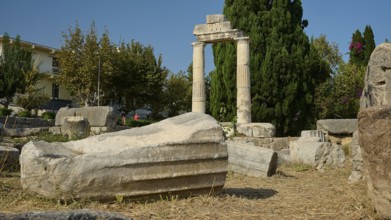 Debris of a fallen column lying on dry ground in front of a stone archway, Ancient Agora, Kos Town,