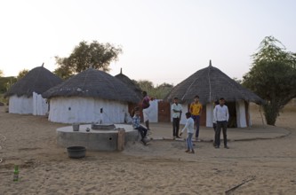 Indian desert dwellers, behind typical circular buildings in the Thar Desert or Great Indian