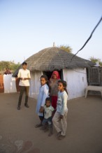Indian desert dwellers, behind typical circular buildings in the Thar Desert or Great Indian