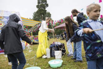 An artist makes soap bubbles with children at Kidzapalooza at the Lollapalooza Festival in the