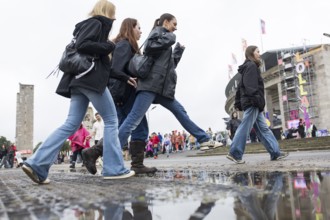 Festival-goers jump over a puddle of rain at the Lollapalooza Festival in the Olympic Stadium and