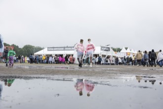 Festival-goers reflected in a puddle at the Lollapalooza Festival in the Olympic Stadium and on the