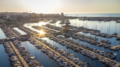 Golden sunrise reflecting on calm waters of torrevieja marina, showcasing docked boats and the