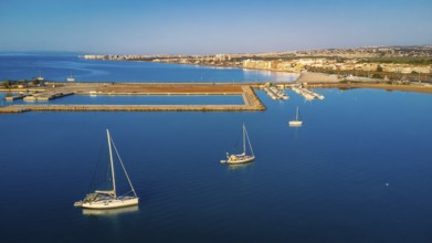 Stunning aerial view of sailboats floating on calm blue water near the coastline of torrevieja