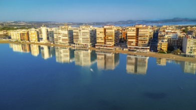 Aerial view of torrevieja skyline reflecting on calm mediterranean sea at sunrise, with colorful