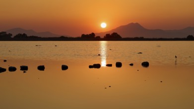 Tranquil landscape with sunset over a lake and distant mountains, salt lake, Tigaki, nature