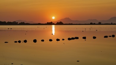 Dramatic sunset over a calm lake with mountain silhouette, salt lake, Tigaki, nature reserve, hydro
