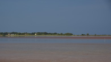 Tranquil coastal scene with blue sky and reflecting water, salt lake, Tigaki, nature reserve, hydro