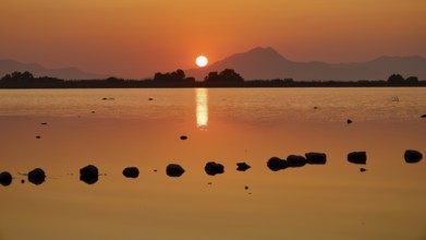 Glistening sunset with warm tones and mountain silhouette, salt lake, Tigaki, nature reserve, hydro