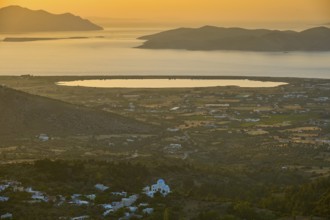 A view of a village and fields in front of the sea at sunset, salt lake, Tigaki, nature reserve,