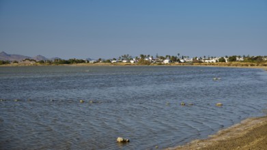 A coastal village on the shore of a lake in calm weather under a blue sky, salt lake, Tigaki,