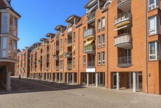 Modern brick architecture, Teerhof peninsula, columns, balconies, cobblestones, street, blue sky,