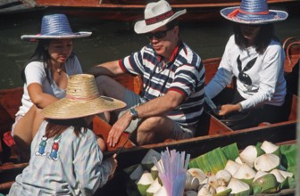 Dealer and customer in their boats at the Damnoen Saduak floating market, Thailand, December 2002,