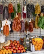 A market stall full of colorful fruits and traditional sweets with a juicer in the foreground,