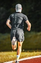 Man in grey running clothes on a red track, looking back, triathlon, Calw, Germany