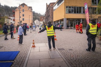 Group of people wearing safety vests at a roadblock in an urban environment, triathlon, Calw,
