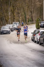 Two runners on a wooded village road with parked cars, triathlon, Calw, Germany