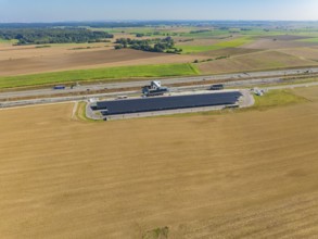Solar system and motorway, surrounded by vast farmland and clear skies, e-charging park,