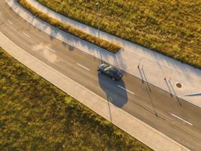 Aerial view of a car on a paved road next to a field in sunlight, BMW i7 electric car, Deer