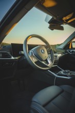 Modern car interior with stylish steering wheel and screens, in sunset light, BMW i7 electric car,