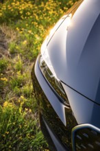 Close-up view of a shiny car with sun reflections on the body in the meadow, BMW i7 electric car,