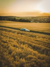 In vast, golden fields during twilight, a car drives through peaceful countryside, BMW i7 electric