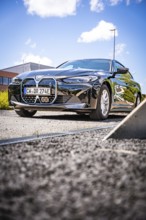 A black car is parked on a quiet road under a blue sky, BMW i7 electric car, Deer E- Carsharing,