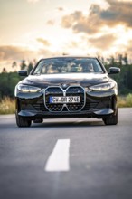 A black car on a country road at sunset with trees in the background, BMW i7 electric car, Deer