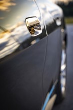Close-up of a car door with sunset reflections on the paint, BMW i7 electric car, Deer