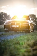 BMW with headlights switched on in the back light of sunset, BMW i7 electric car, Deer