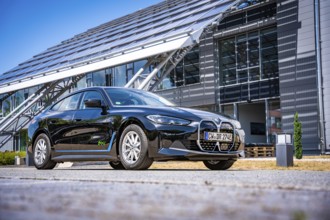 Black car next to a modern building with solar panels and clear sky, BMW i7 electric car, Deer