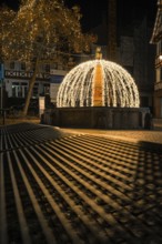 Atmospheric night view of a festive fountain with lights and shadows in an old town, Calw, Black