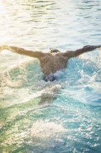 A swimmer in a pool laps in sunlight and whirls up water, triathlon, Calw, Germany