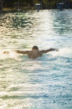A swimmer swims in the pool, the afternoon sun reflecting on the water, Triathlon, Calw, Germany