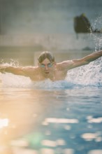 A swimmer wearing sunglasses in the pool shows a powerful swimming movement, Triathlon, Calw,